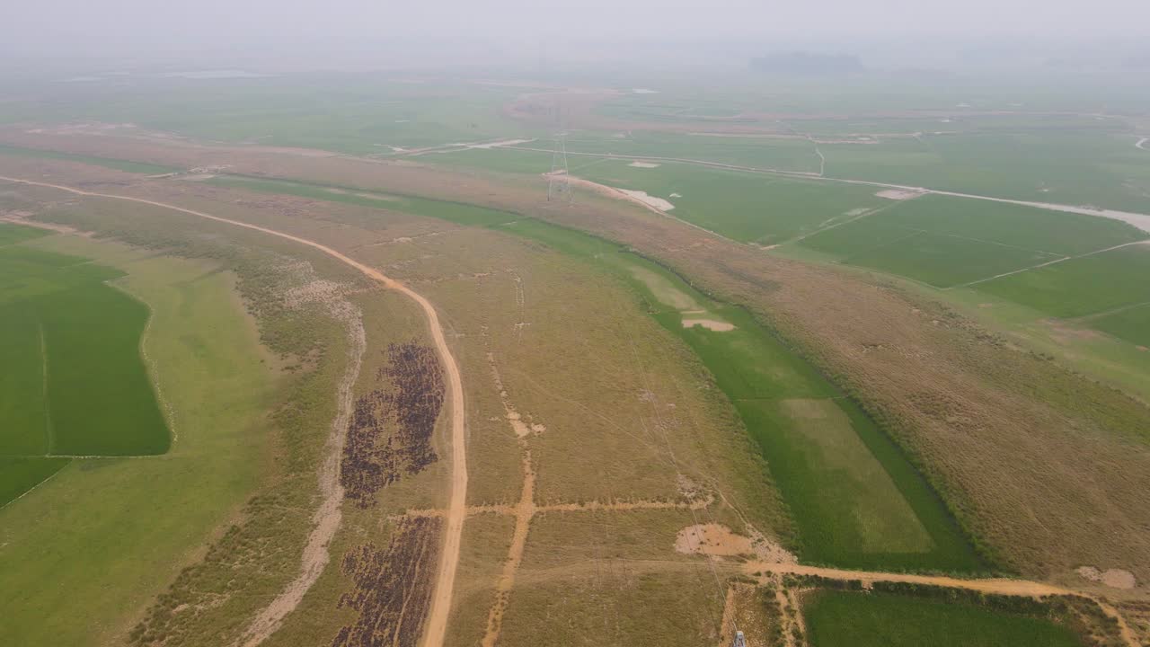 vista aérea volando sobre un poste eléctrico en las tierras agrícolas brumosas de la india rural