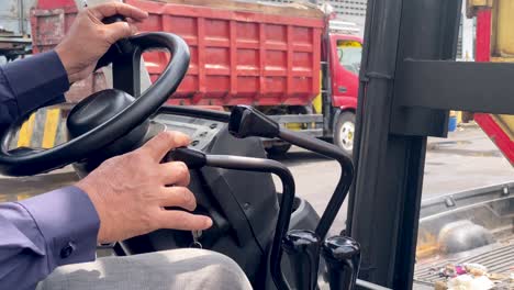 the hands of a worker operating a forklift