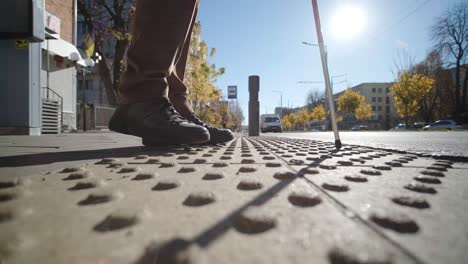 lone blind man detecting tactile tiles, walking to pedestrian crossing safe road