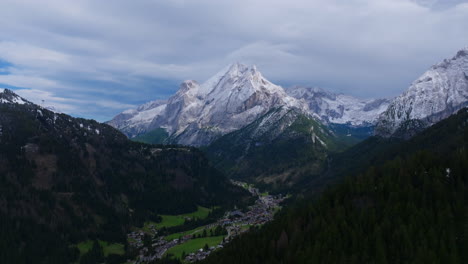 imágenes aéreas volando lejos de piccolo vernel, montaña en la cordillera de marmolada de los dolomitas en italia con pequeños pueblos debajo de ella.