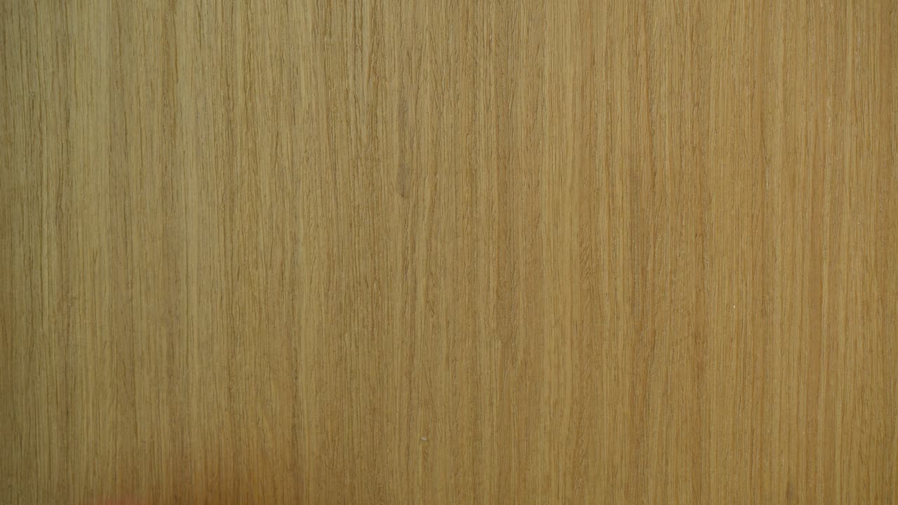 Detailed close-up shot of a pink sticky note on a wooden door with 'At the Gym' written removed by a person's hand. Warm lighting and vertical composition enhance the focus in this intimate scene