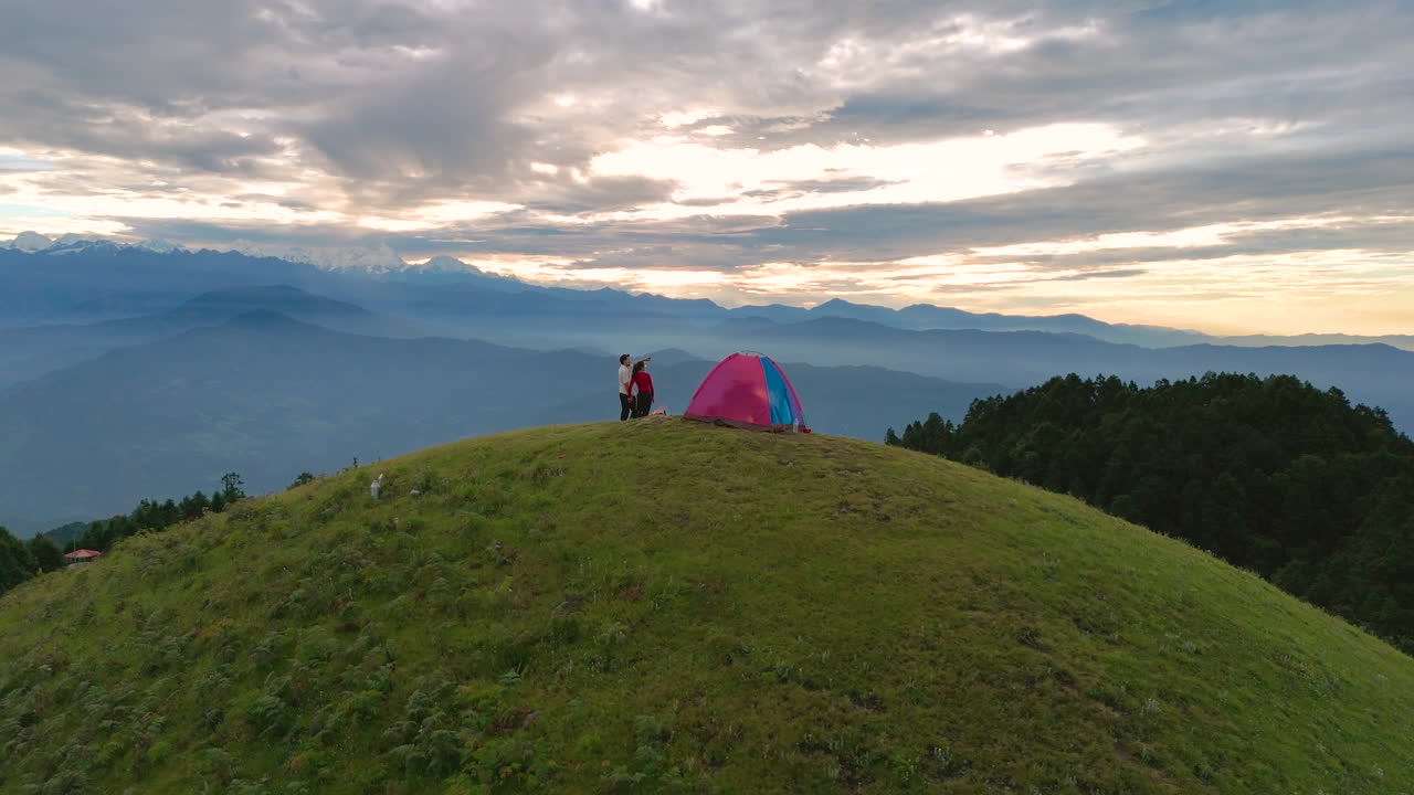 드론 촬영은 네팔의 도라카 (dolakh) 의 세일롱 언덕에서 캠핑하는 커플을 포착합니다. 산맥에 둘러싸여 천상의 환경에서 불꽃을 즐기고 자연에서 평화롭고 만적 인 리티 시간을 보내십시오.