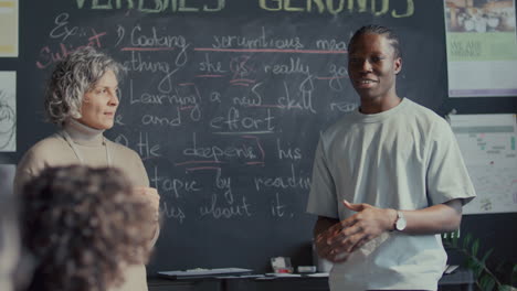 african american student reciting at blackboard during english lesson