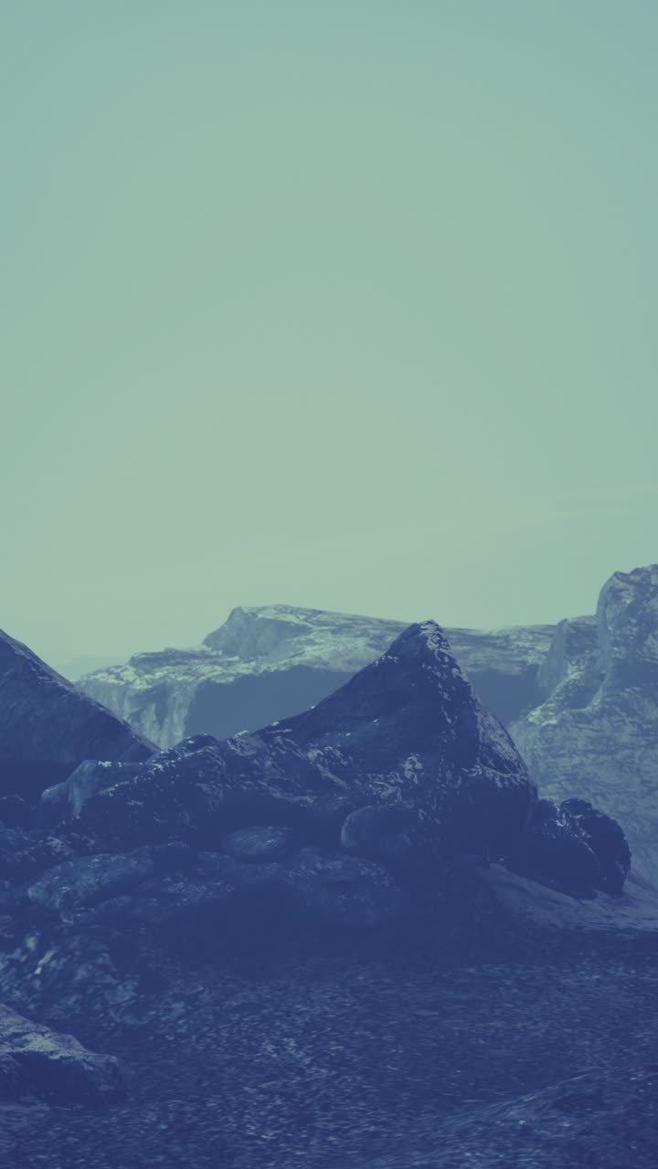 Landscape of rugged rocks under misty sky with soft blue tones at twilight
