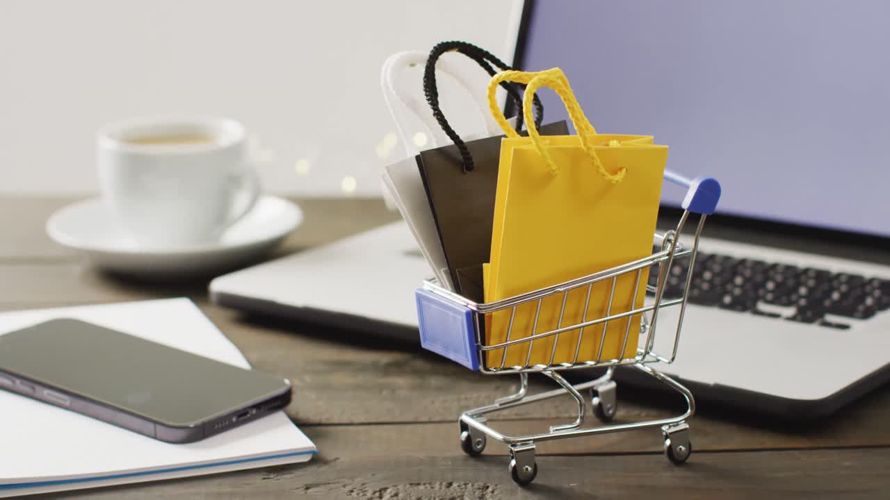 bolsas de regalos en el carrito de compras en el escritorio con teléfono inteligente y portátil