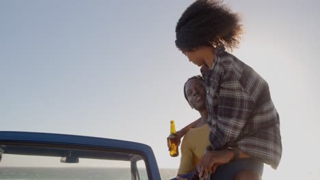 Woman-on-mans-lap-sitting-on-a-pickup-truck-at-beach-4k