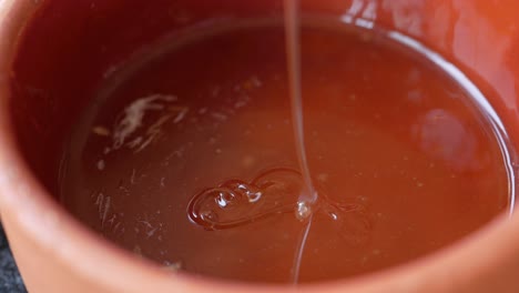 pouring honey into a terracotta bowl