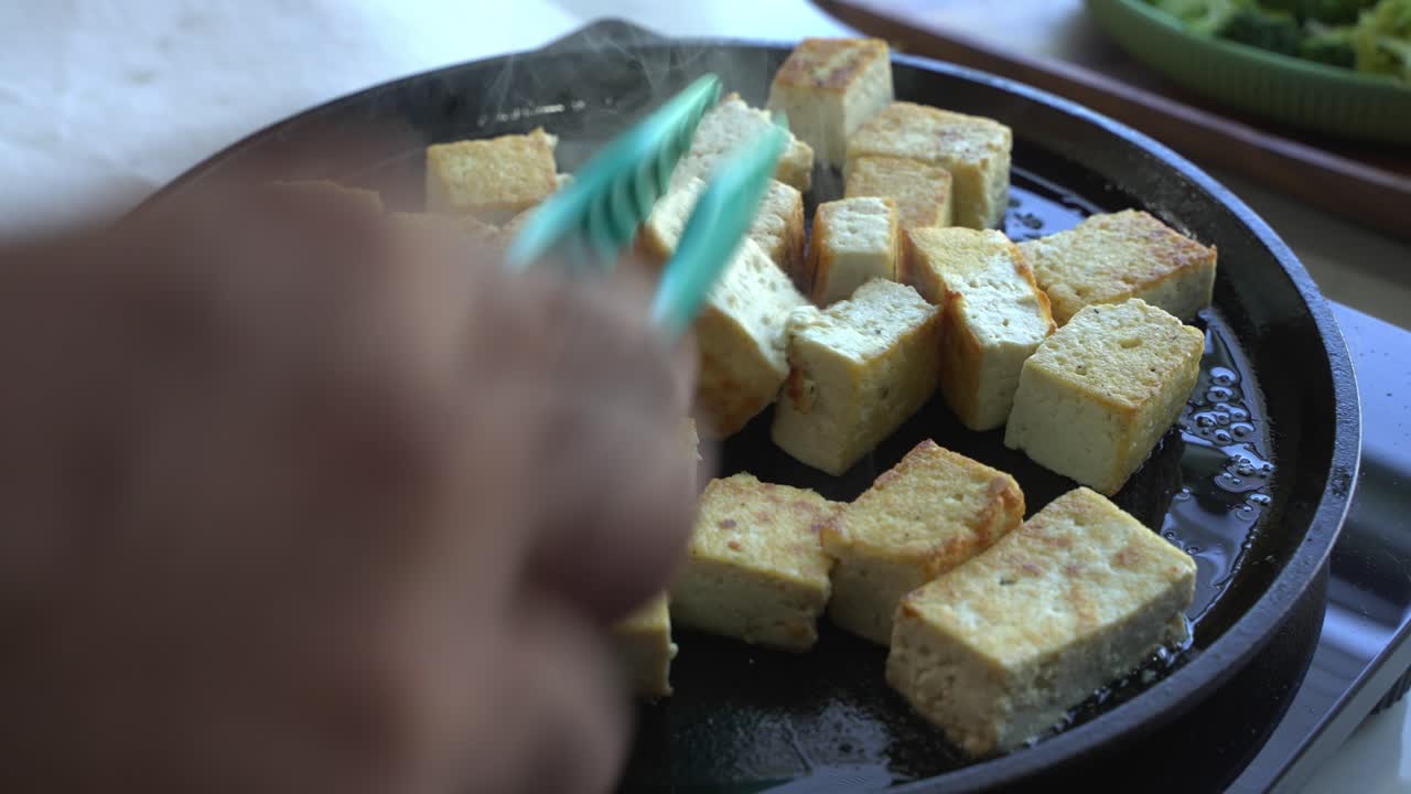 Tofu being fried on a cast iron special ingredients to cook a meal two cans of beans rice plantain avocado red onion and cilantro