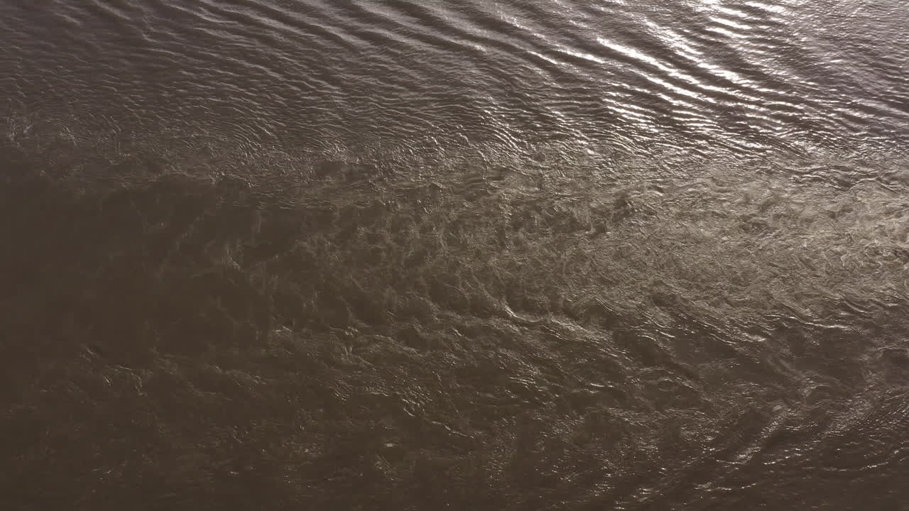 Barge wake on hudson river ripples on the muddy water surface