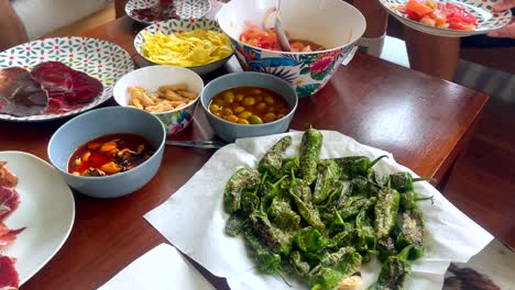 table with spanish tapas including jamón, padrón peppers, and olives