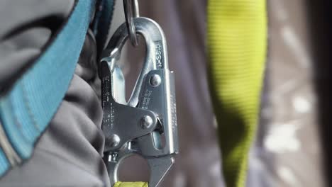 A-warehouse-worker-wears-an-industrial-safety-tether-clasp-while-driving-a-forklift-stock-picker-truck-down-an-isle-of-boxed-inventory-stock-inside-a-distribution-centre