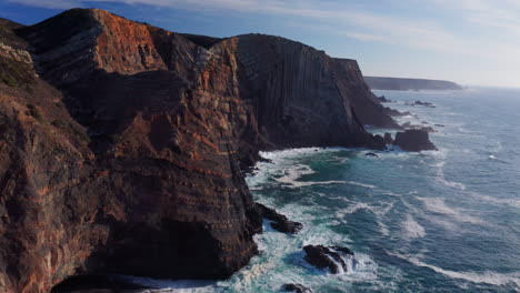 cinematic drone circle showing gigantic lighting cliff coastline with ocean waves from atlantic during sunny day