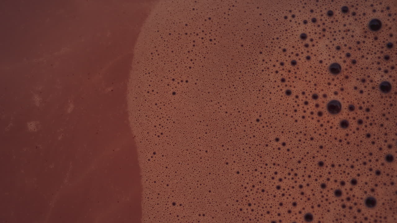 Cinematic shot of a boat propeller near a red hull, reflecting vibrant colors on the water surface