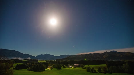 Timelapse-En-La-Noche-De-Un-Paisaje-Idílico-Cerca-Del-Lago-Attersee-Con-Luna-Brillante-Y-Estrellas-Centelleantes-Con-Vistas-Al-Paisaje-Montañoso-Con-Densos-Bosques-Y-Majestuosas-Montañas-Y-Nubes-Pasajeras