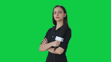 Portrait-of-Indian-female-news-reporter-standing-crossed-hands-Green-screen