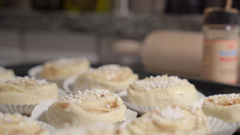 Slide-shot-of-cinnamon-buns-on-a-tray-with-baking-utensils