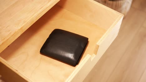 open wooden drawer with black wallet inside
