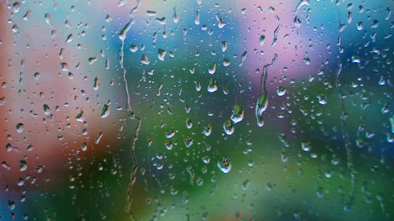 Drops of rain on window glass on blur background. Rainy weather. Rain droplets flowing down on glass window at rainy day. Close-up.