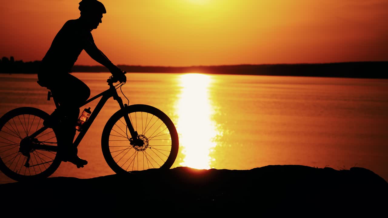 Man ride a bicycle at sunset. Silhouette of a man rides a bike at sunset