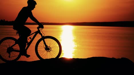 man ride a bicycle at sunset. silhouette of a man rides a bike at sunset