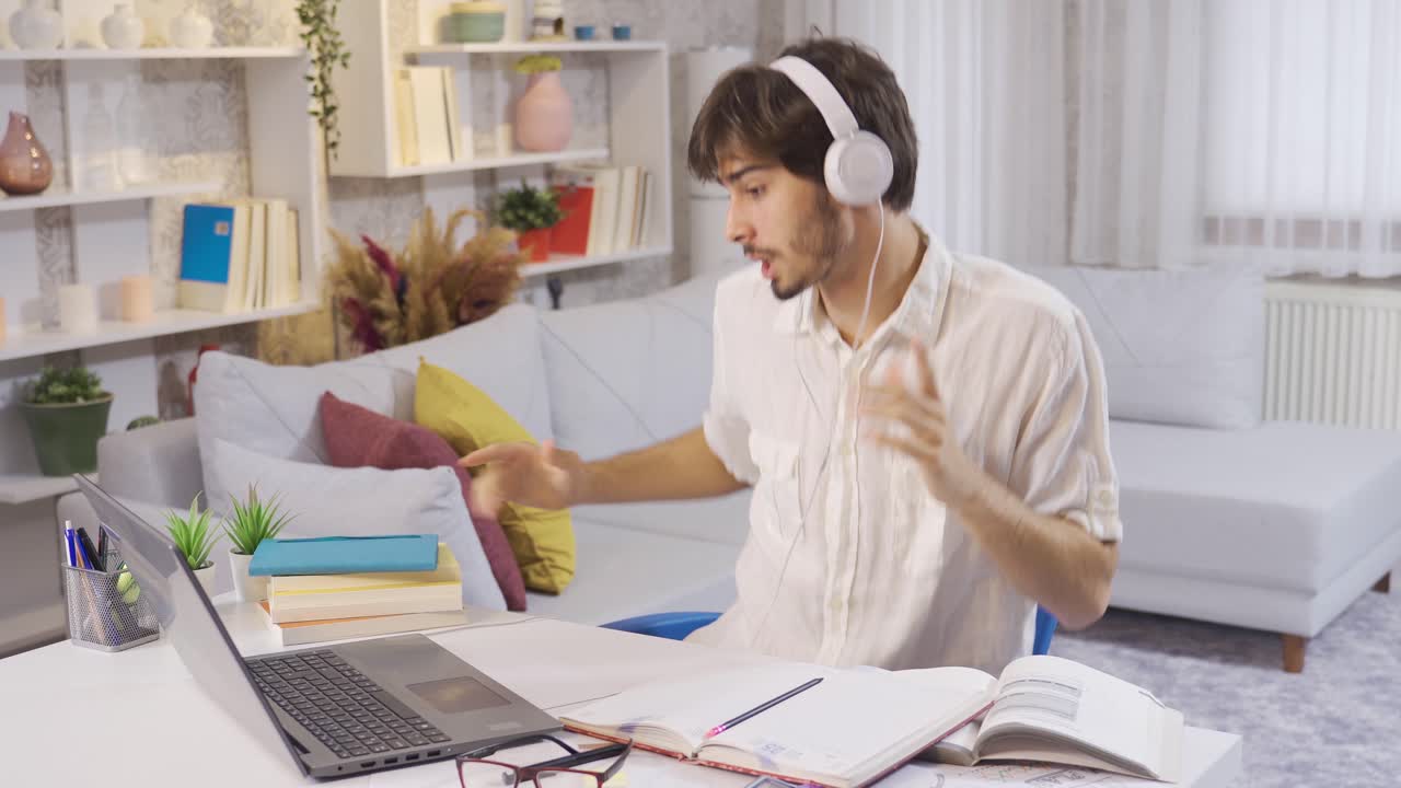 Young male student listening to music studying at home.