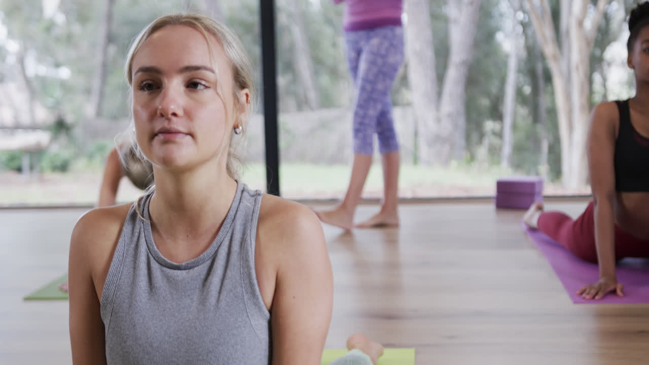 mujer caucásica sonriendo a la cámara mientras practica la postura de cobra en la clase de yoga