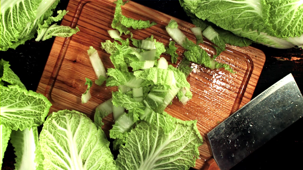 Chopped Chinese Cabbage Falling onto a Wooden Cutting Board