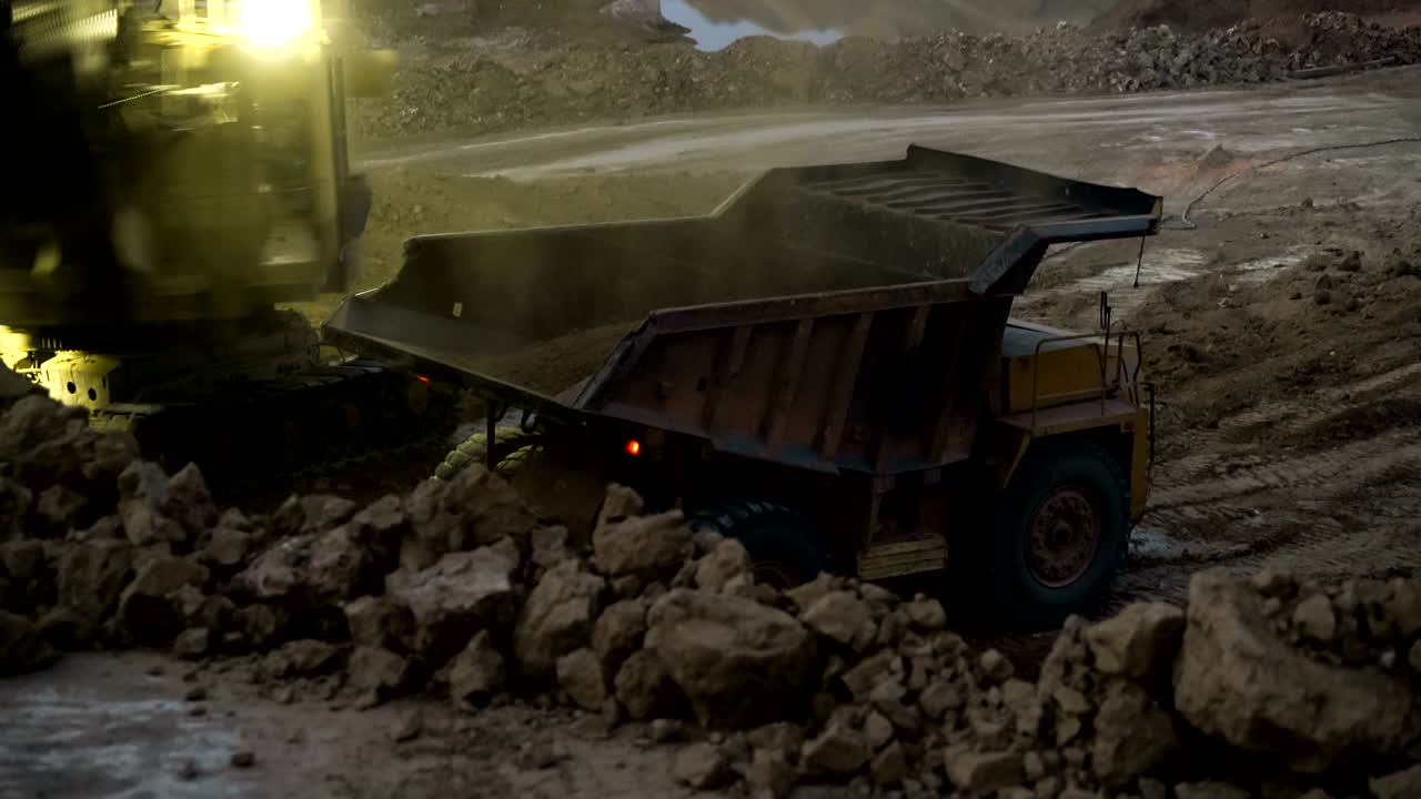 Time lapse of excavator loading ore into dump-trucks at the sunset.