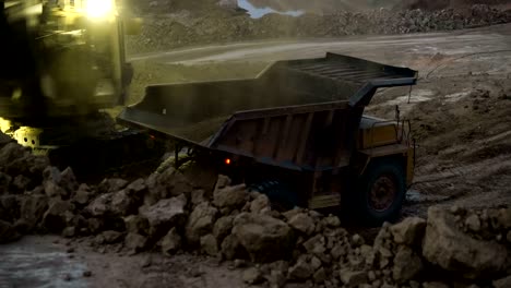 time lapse of excavator loading ore into dump-trucks at the sunset.