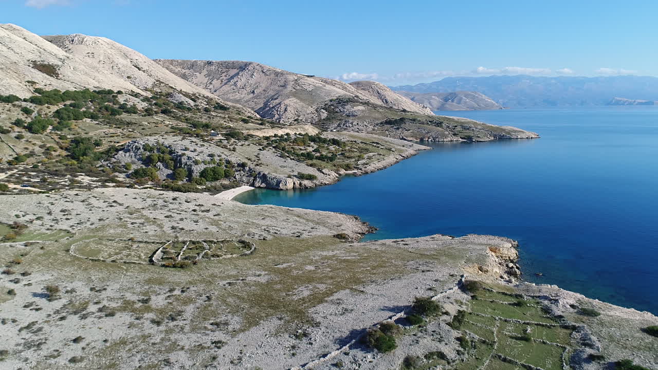 Panoramic view of a barren coastal landscape with dry trees and clear blue sea water