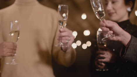 close up of happy friends toasting and drinking champagne at new year's eve party