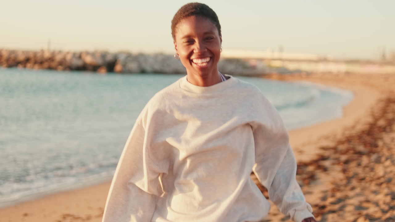 Glad ung afrikansk-amerikansk kvinne løper og ler på stranden