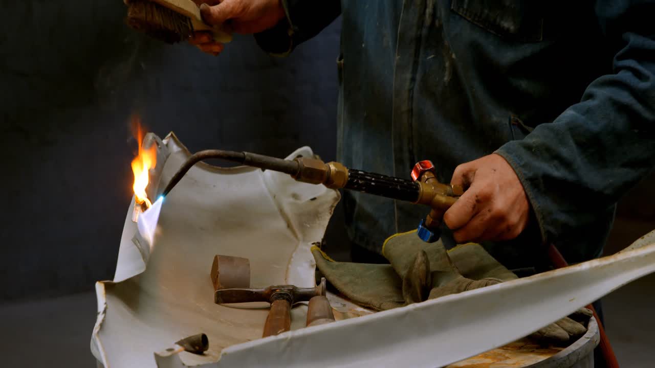 Mechanic using wielding torch on a car part 4k