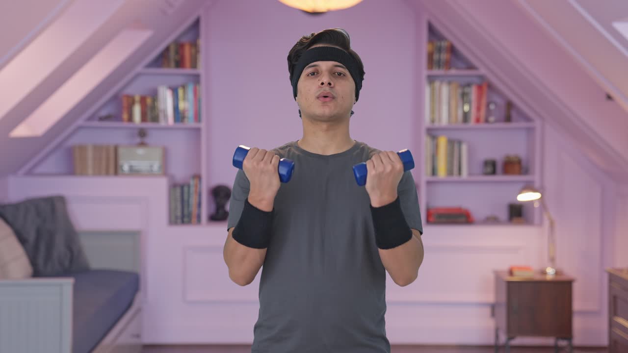 인디언 남자가 덤벨을 들어 올리고 운동을 하고 있습니다.