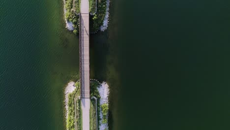 Offset-aerial-shot-of-woman-running-across-a-small-bridge-spanning-a-lake