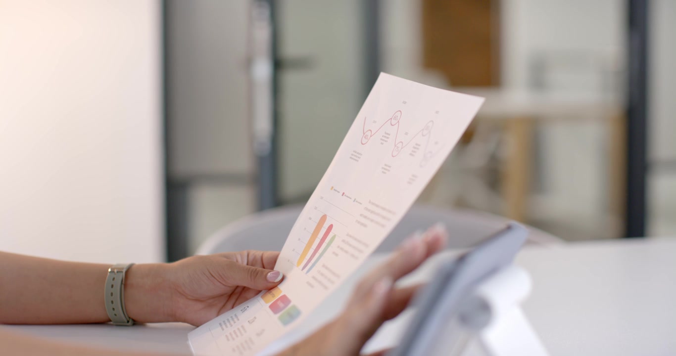 Hands with mint band are lifting and aligning report for inspection to tablet for chart comparison