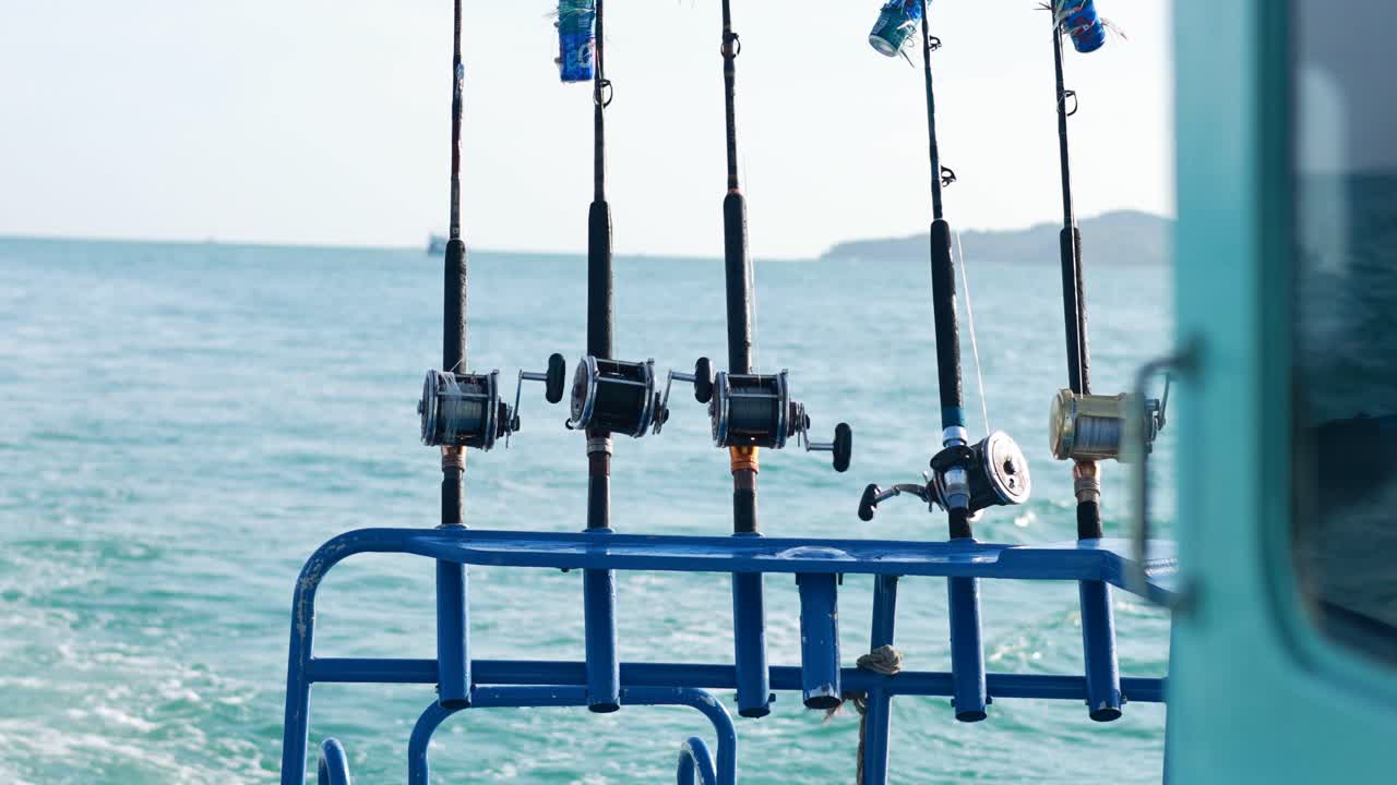 Fishing rods lined up on a boat against the backdrop of Phuket's ocean. Calm sea, bright daylight, and serene atmosphere