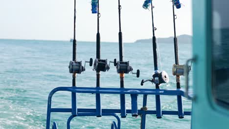 fishing rods lined up on a boat against the backdrop of phuket's ocean. calm sea, bright daylight, and serene atmosphere