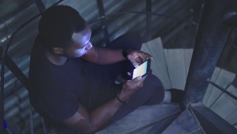 man using phone on spiral stairs at night