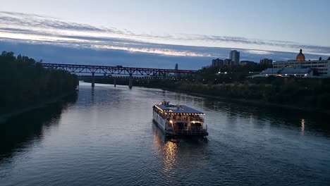 time lapse north saskathchewan river boat dining party on a summer evening inbetween the water dale bridge and the high level bridge in downtown edmonton canada with a blue gradaition sky