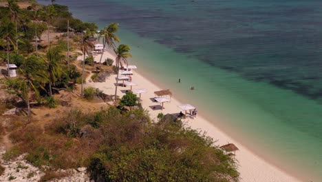 Philippines-Camotes-islands-with-sunbrellas-along-the-turquoise-ocean-shore,-Aerial-dolly-out-shot