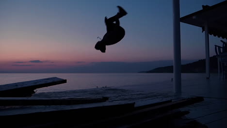 young male traveler making a frontflip at the seaside