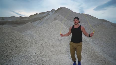 man jumping rope in a gravel pit