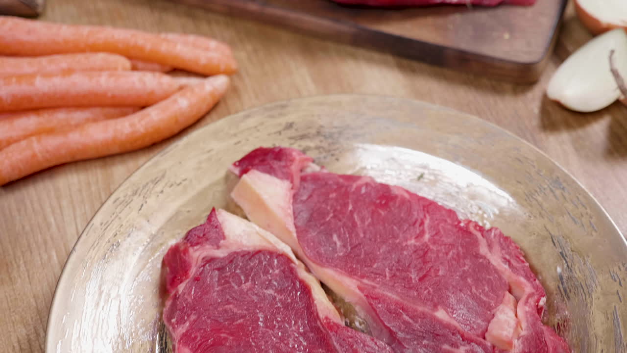 Bistecca di manzo cruda su un tagliere con erbe e verdure