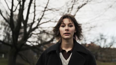 young woman in a black coat walking in a park in autumn in afternoon