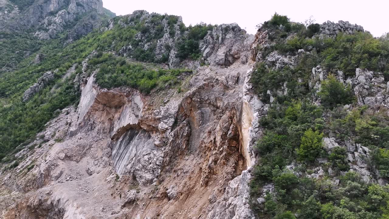 toma aérea de erosión en la ladera con terreno rocoso y bosque cerca de la montaña
