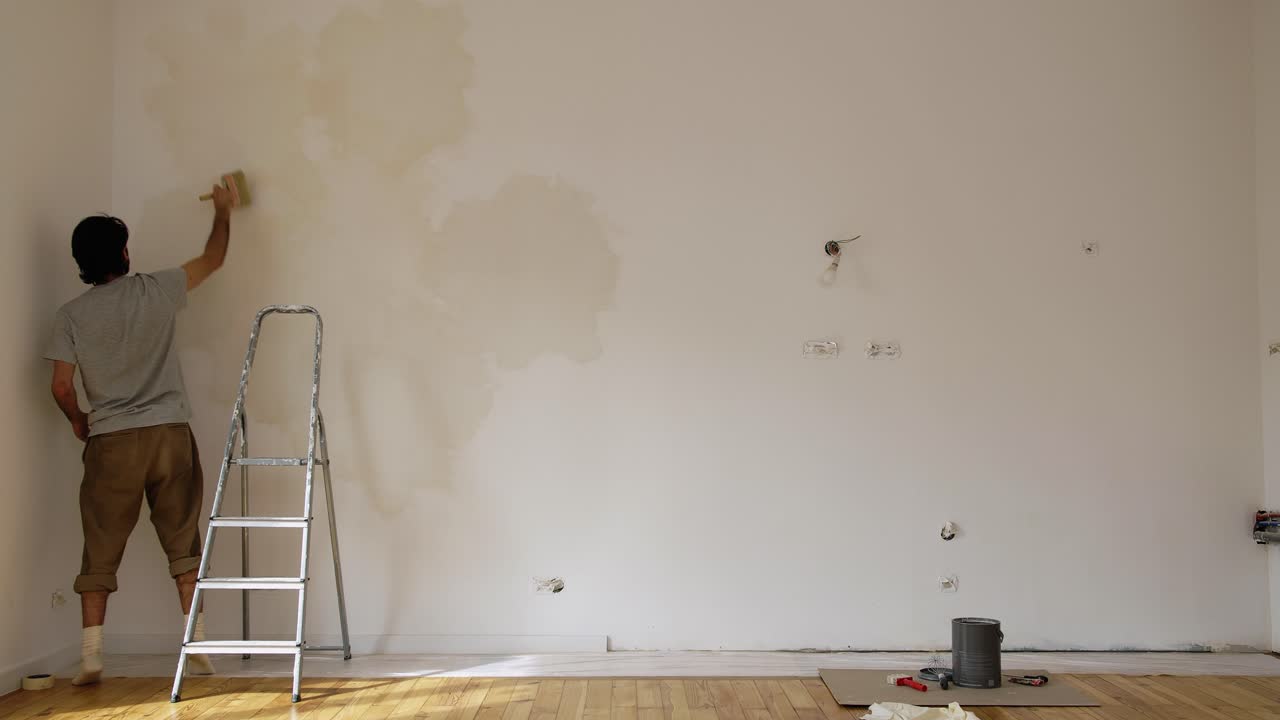 Scene Of A Man Limewash Painting A Wall Of A Renovated Room