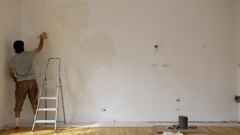 scene of a man limewash painting a wall of a renovated room