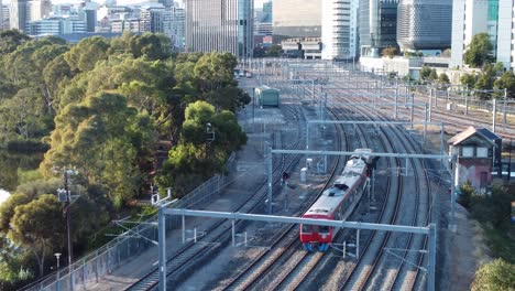 Tren-Eléctrico-De-Pasajeros-Del-Metro-De-Adelaida-Moviéndose-Hacia-La-Cámara-Con-Edificios-Y-El-CDB-De-Adelaida-Al-Fondo