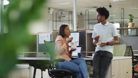 video of diverse businesswoman and businessman drinking coffee, eating and talking in office